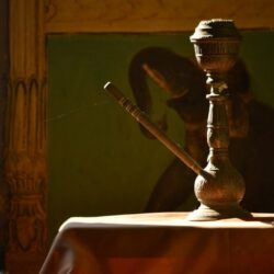 Antike orientalische Wasserpfeife auf einem Tuch vor dunklem Gemälde